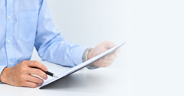 Professional signing a patent application on a clipboard